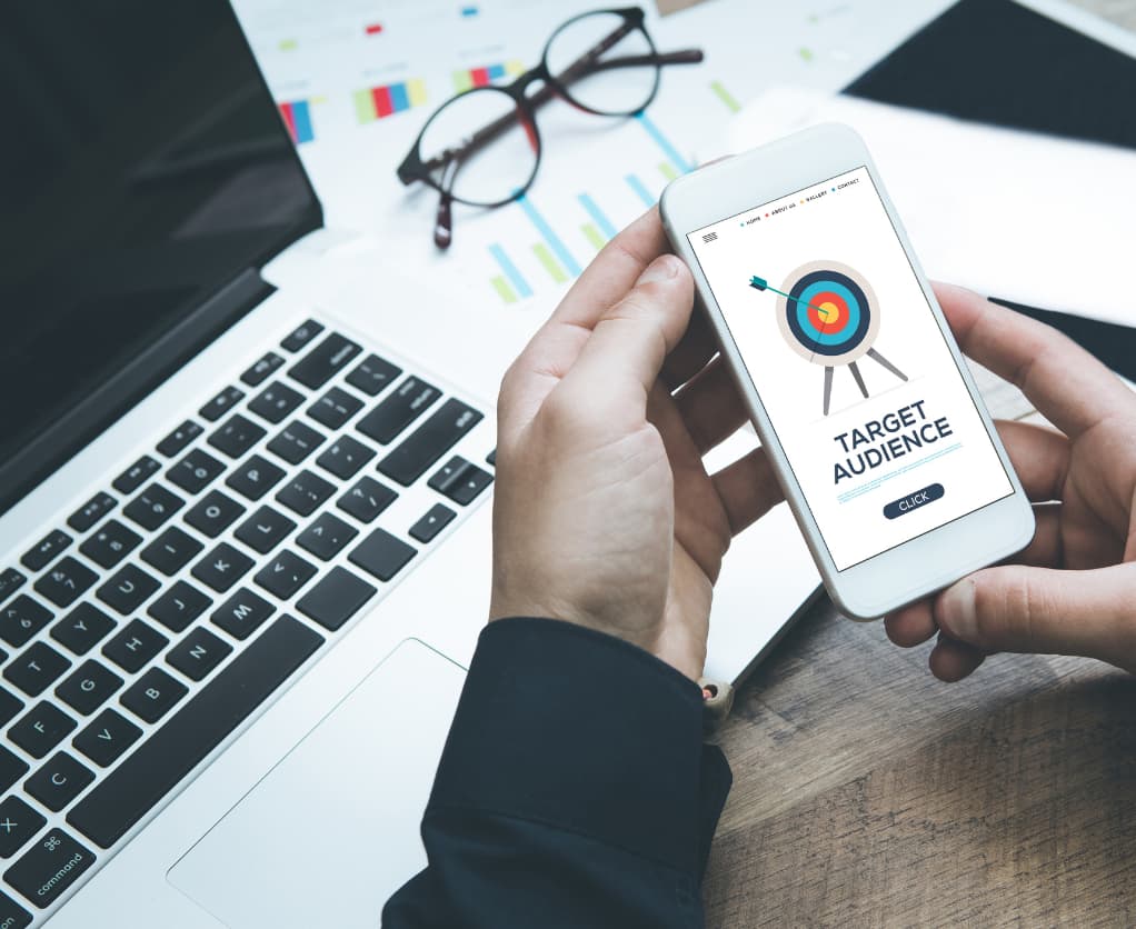 Zielscheibe auf Smartphone, im Hintergrund Laptop