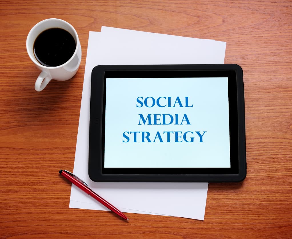 Tablet mit "Social Media Strategie", Papier, Bleistift, Kaffee