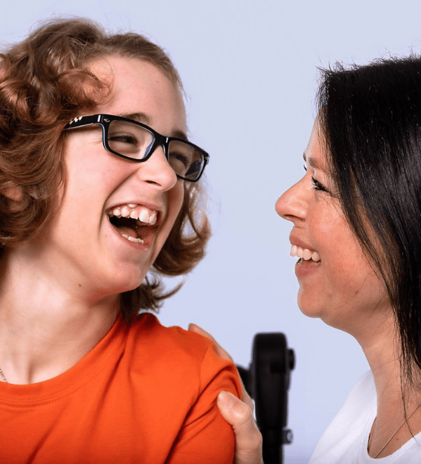 Beinträchtigtes Kind lächelt seine Mutter zu Hause an